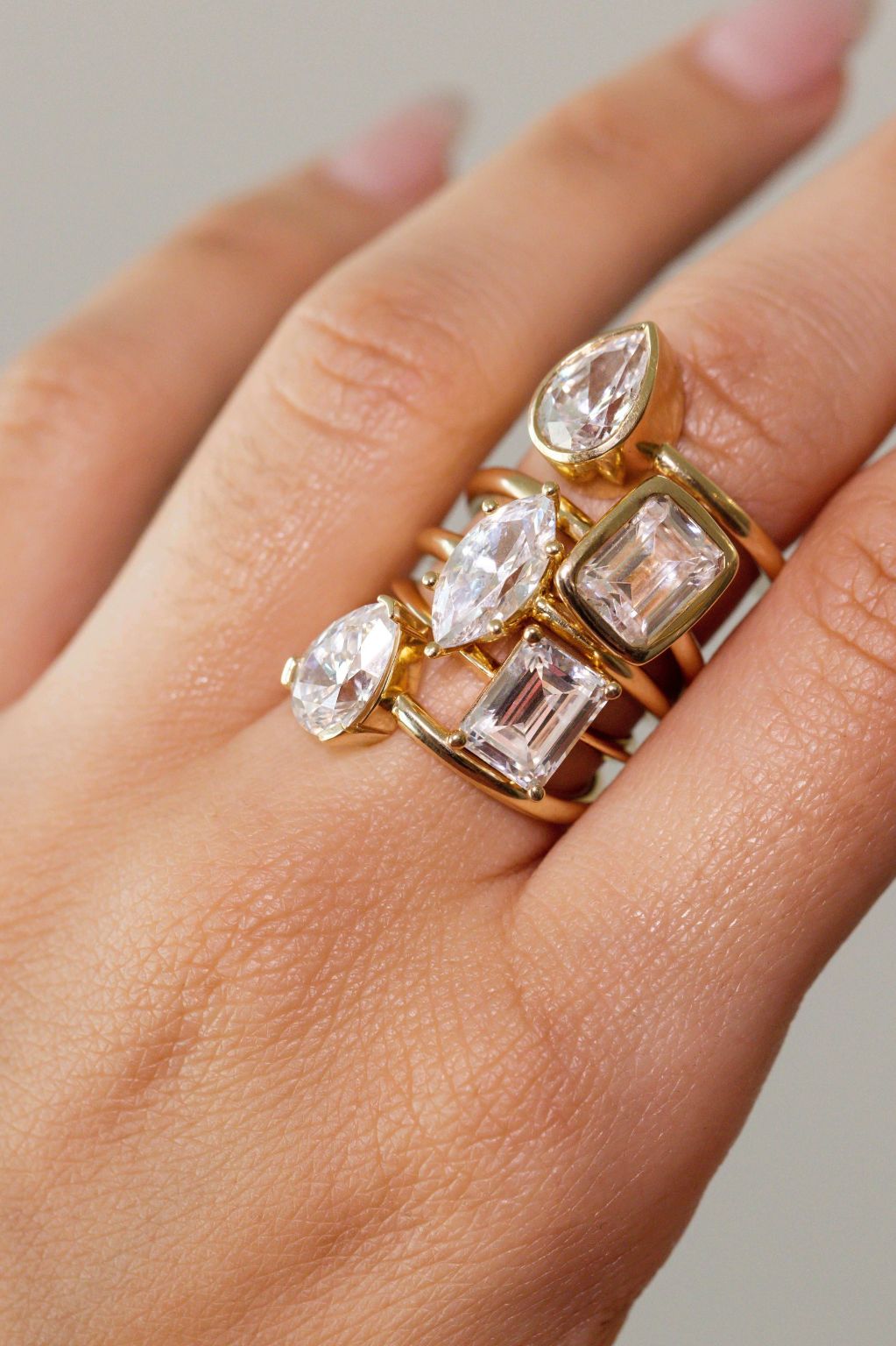 Close up of woman's hand with multiple white diamond rings stacked on the same finger.