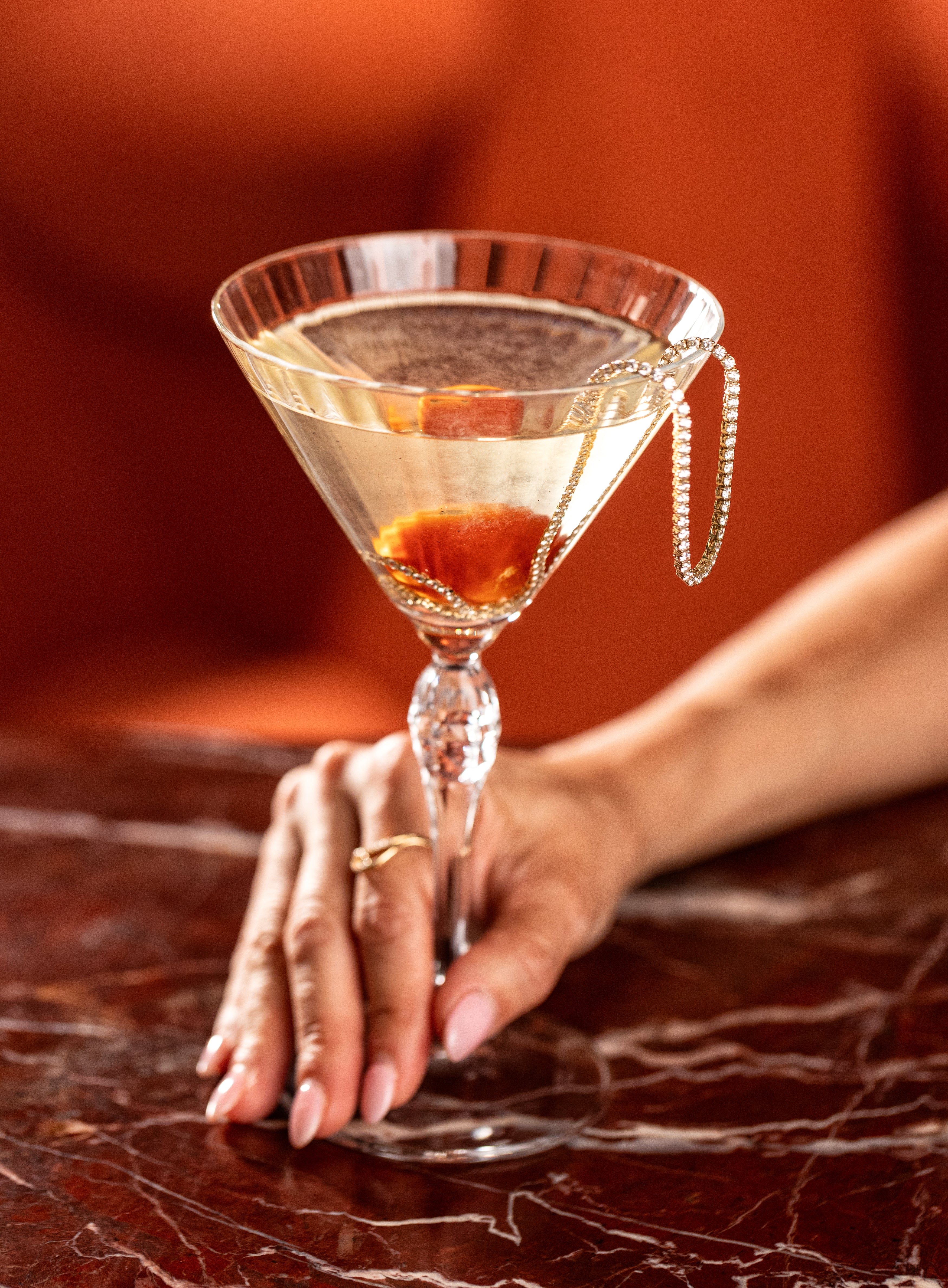 Close up of hand holding The Marrow x Adalina Marrow Martini with a Tennis Necklace coming out of the glass