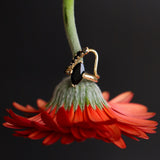 flat lay of Black Onyx Noelle Ring styled on a flower stem, with the Black Diamond Lucy Wave Band