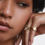 Close up of woman resting hand against her face, spotlighting the Crescent Moon Signet on her pinky ring