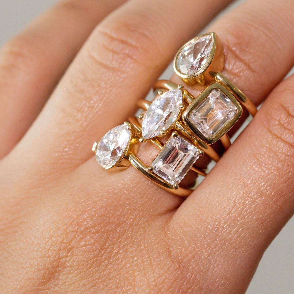 close up of woman's hand with multiple white diamond rings stacked on one finger