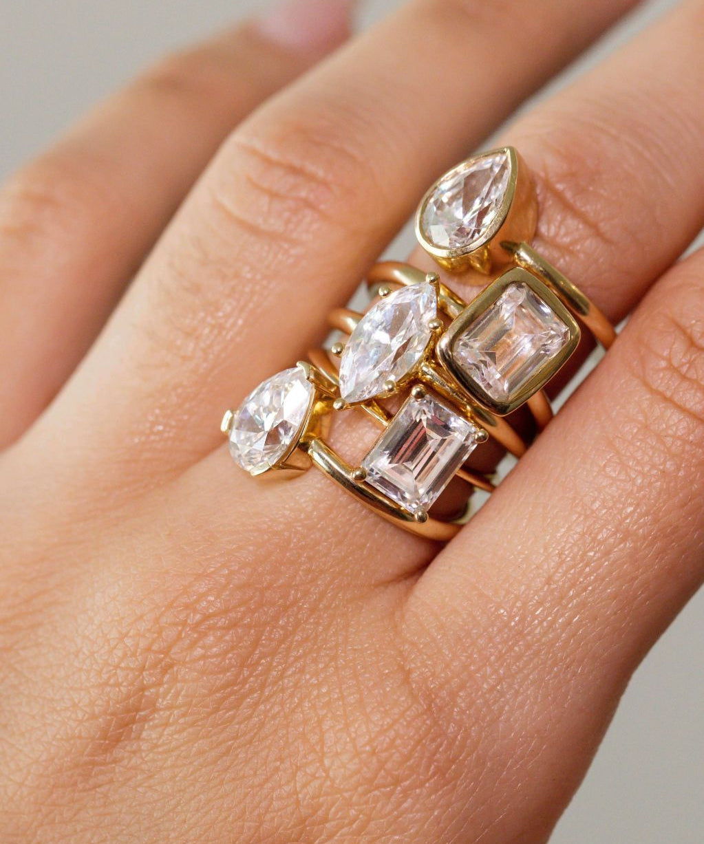 close up of woman's hand with multiple white diamond rings stacked on one finger