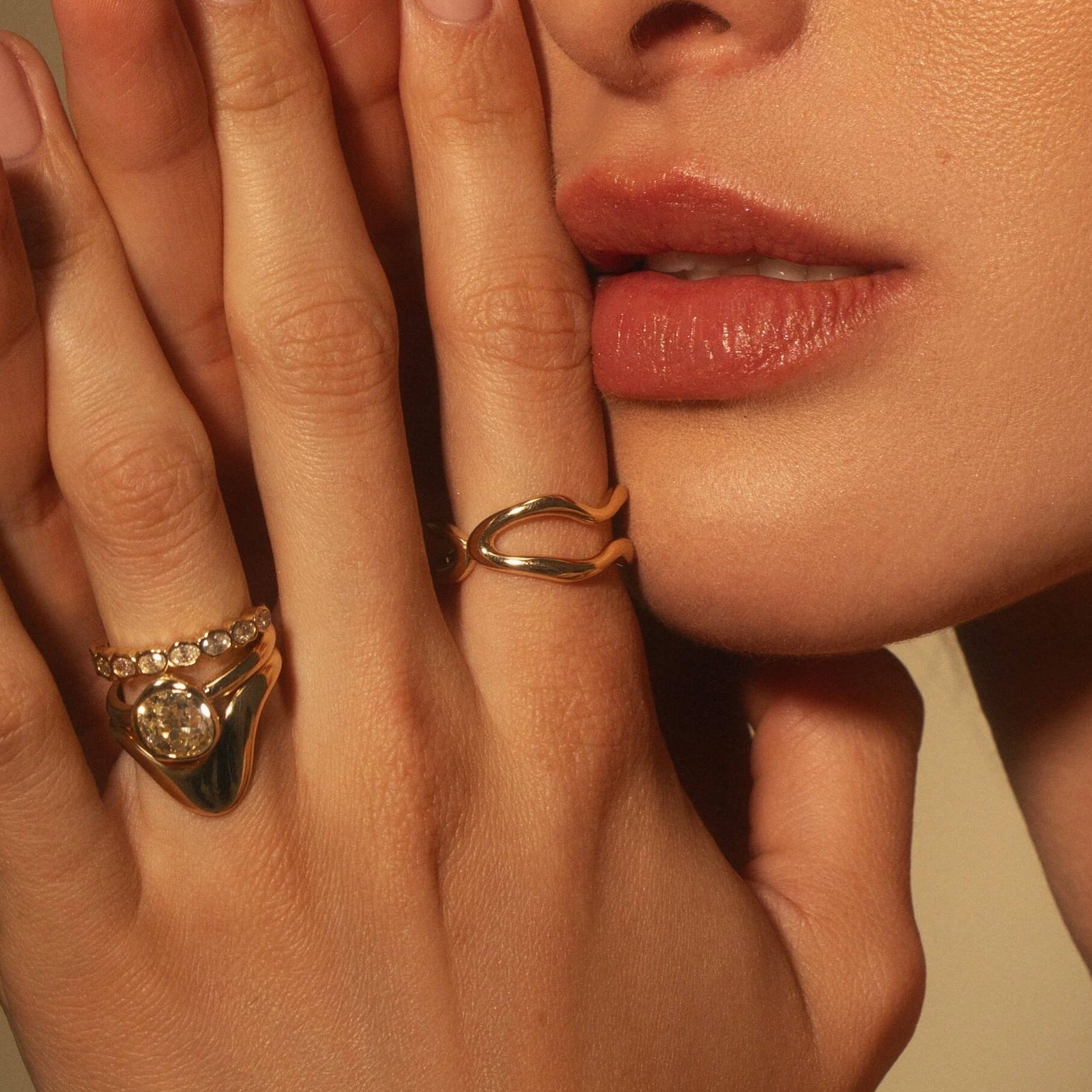 CLose up of woman wearing the Asymmetrical Sculpted Band, Freeform Ring, White Diamond Abstract Bezel Band and an Abstract Bezel Diamond Engagement Ring