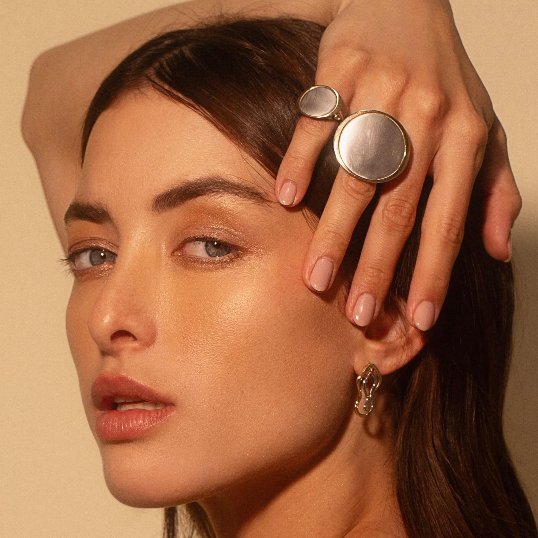 Woman with hand over her head, wearing the Medium Kelly Statement Ring + The Large Kelly Statement Ring