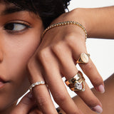 Close up of woman resting hand against her face with multiple Marrow Fine rings styled, the Newport Beach Exclusive Ring on her pinky