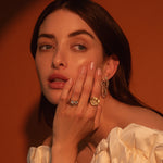 Close up of woman resting hand against her face, highlighting Marrow Fine rings and earrings styled