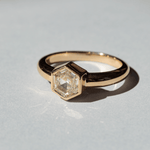 Image of a Marrow Fine one of a kind diamond solitaire ring. The center white diamond is a hexagon cut and bezel set in 14k yellow gold. 