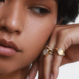 Close up of woman resting her hand against her face, featuring multiple Marrow Fine rings styled 