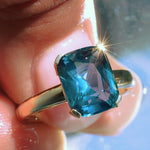 close up of hand holding a sapphire solitaire ring from to the sea collection