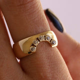 Image of finger with the Old Cut Diamond Selene Cigar Band in yellow gold. There is 4 diamonds total on this wide cigar band that are set in the shape of a 'U'