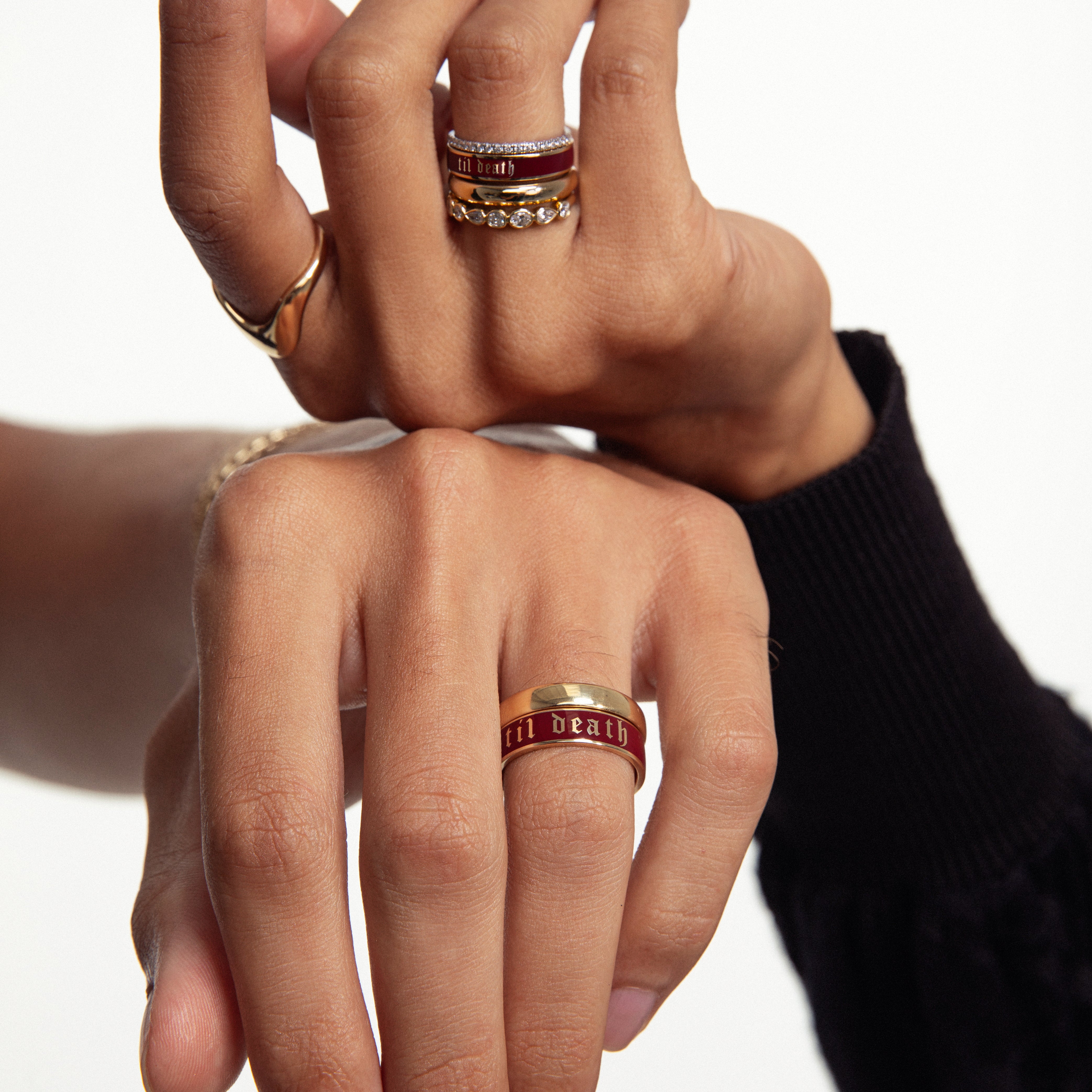 Two hands resting on top of each other, featuring multiple style Marrow Fine Rings