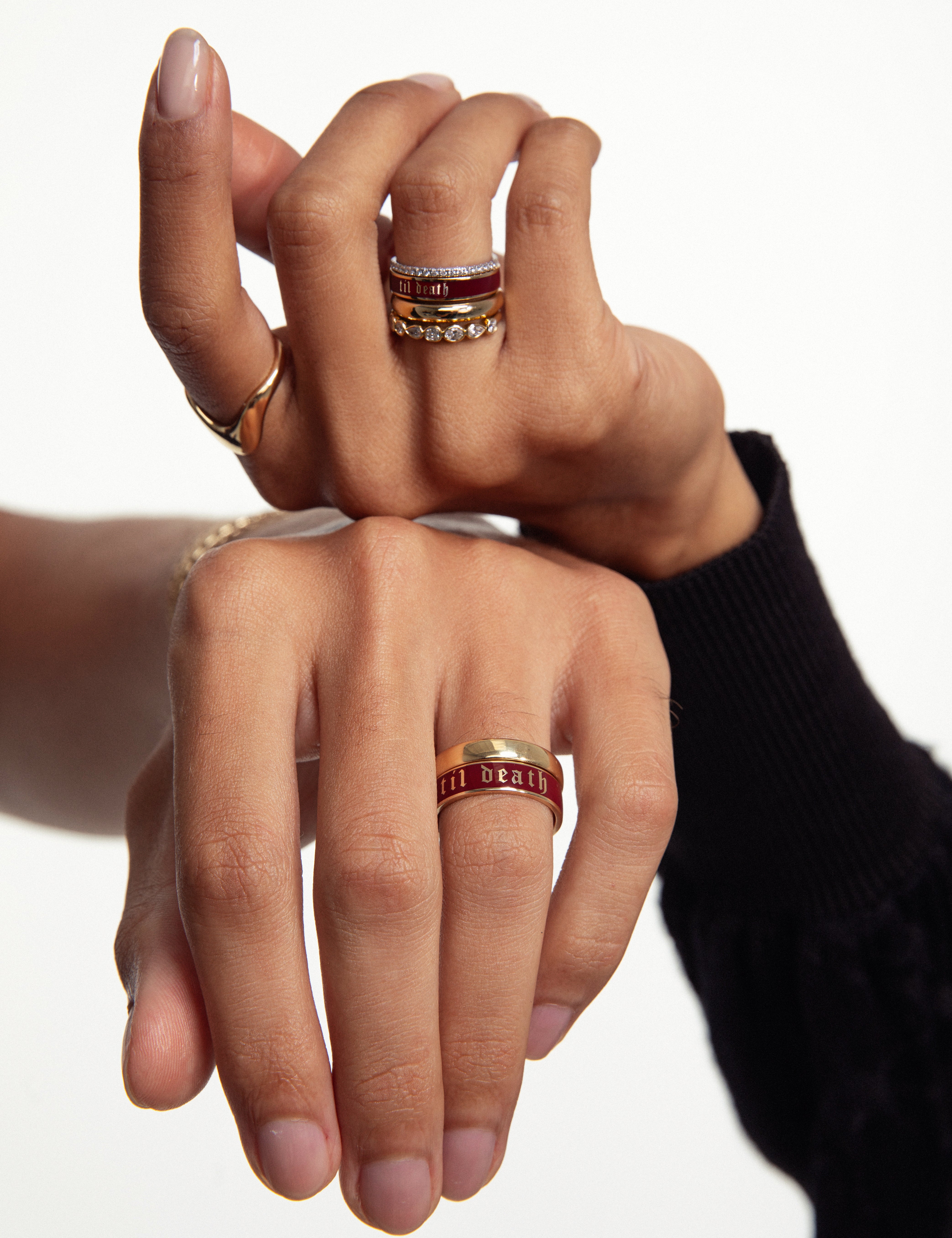 Two hands resting on top of each other, featuring multiple style Marrow Fine Rings